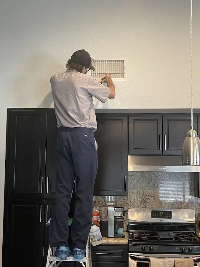 Technician inspecting an air vent during HVAC service in Fairhaven
